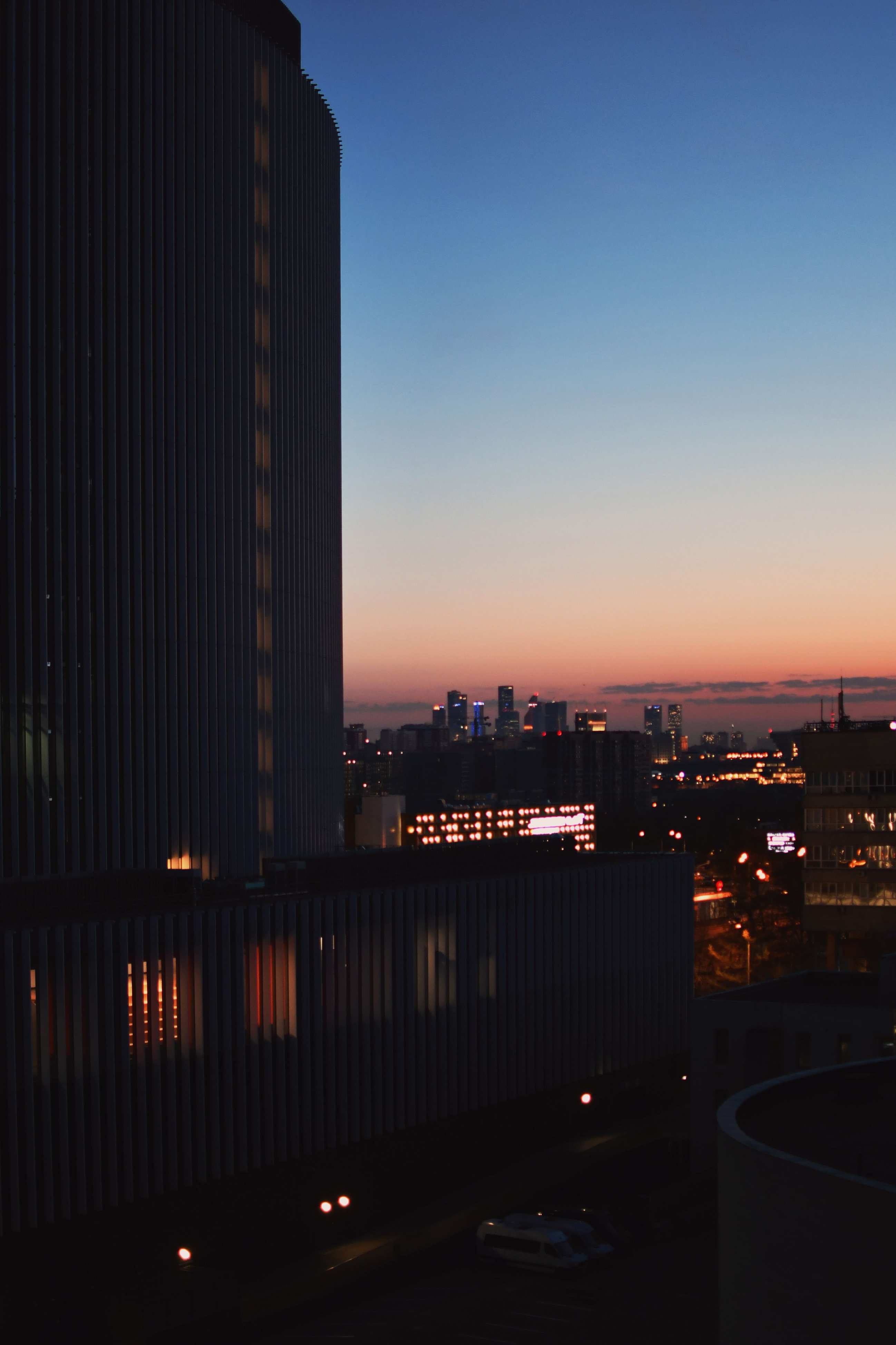 Silhouette einer Stadtskyline bei einsetzender Dunkelheit mit klarer Luft und beleuchteten Gebäuden